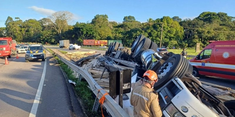 Caminhão carregado de madeira capota na BR-230 e motorista fica preso às ferragens