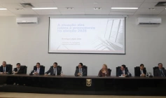 A imagem registra uma mesa composta por nove autoridades, sendo oito homens e uma mulher