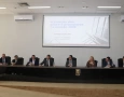 A imagem registra uma mesa composta por nove autoridades, sendo oito homens e uma mulher